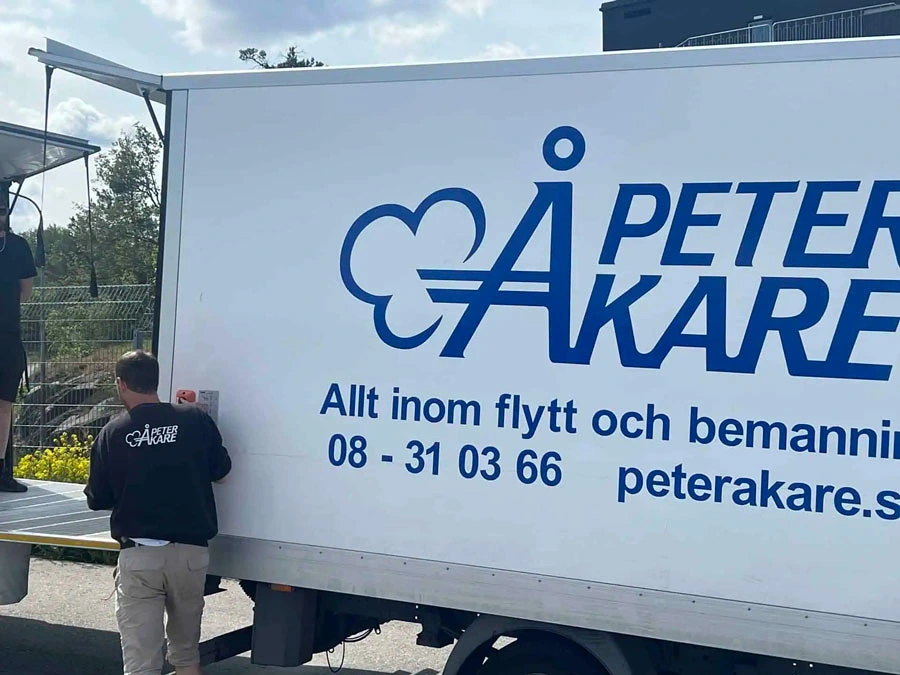 En vit lastbil med Peter Åkare-logotyp och kontaktuppgifter.